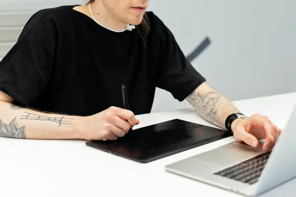 person using drawing tablet in front of laptop