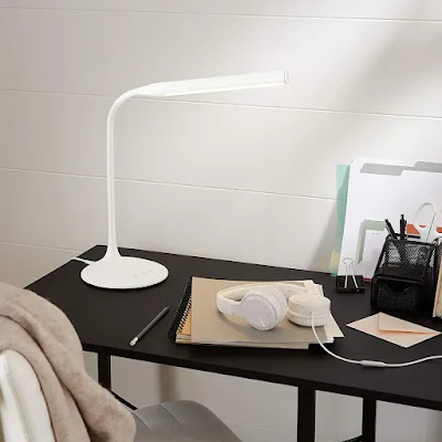 led desk lamp on top of table with book