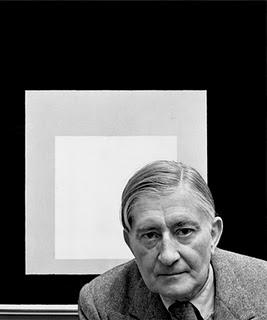 Portrait of Josef Albers standing in front of one of his paintings from Homage to the Square