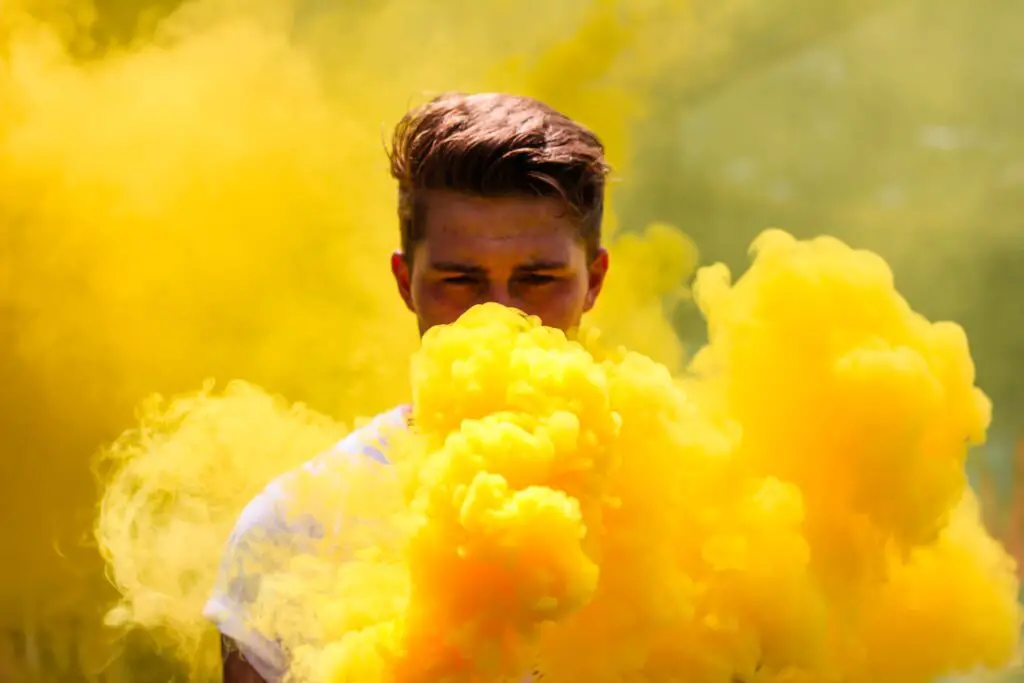 Man hiding behind yellow-colored smoke